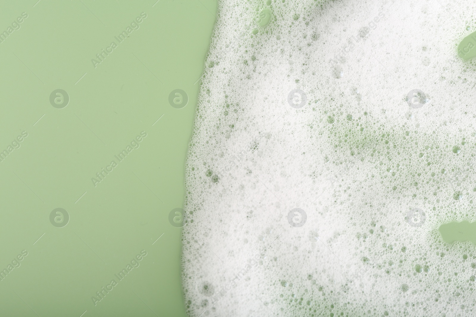 Photo of White fluffy foam on green background, top view. Space for text