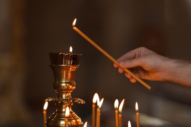 Photo of Man lighting candle near stand in church, closeup. Baptism ceremony