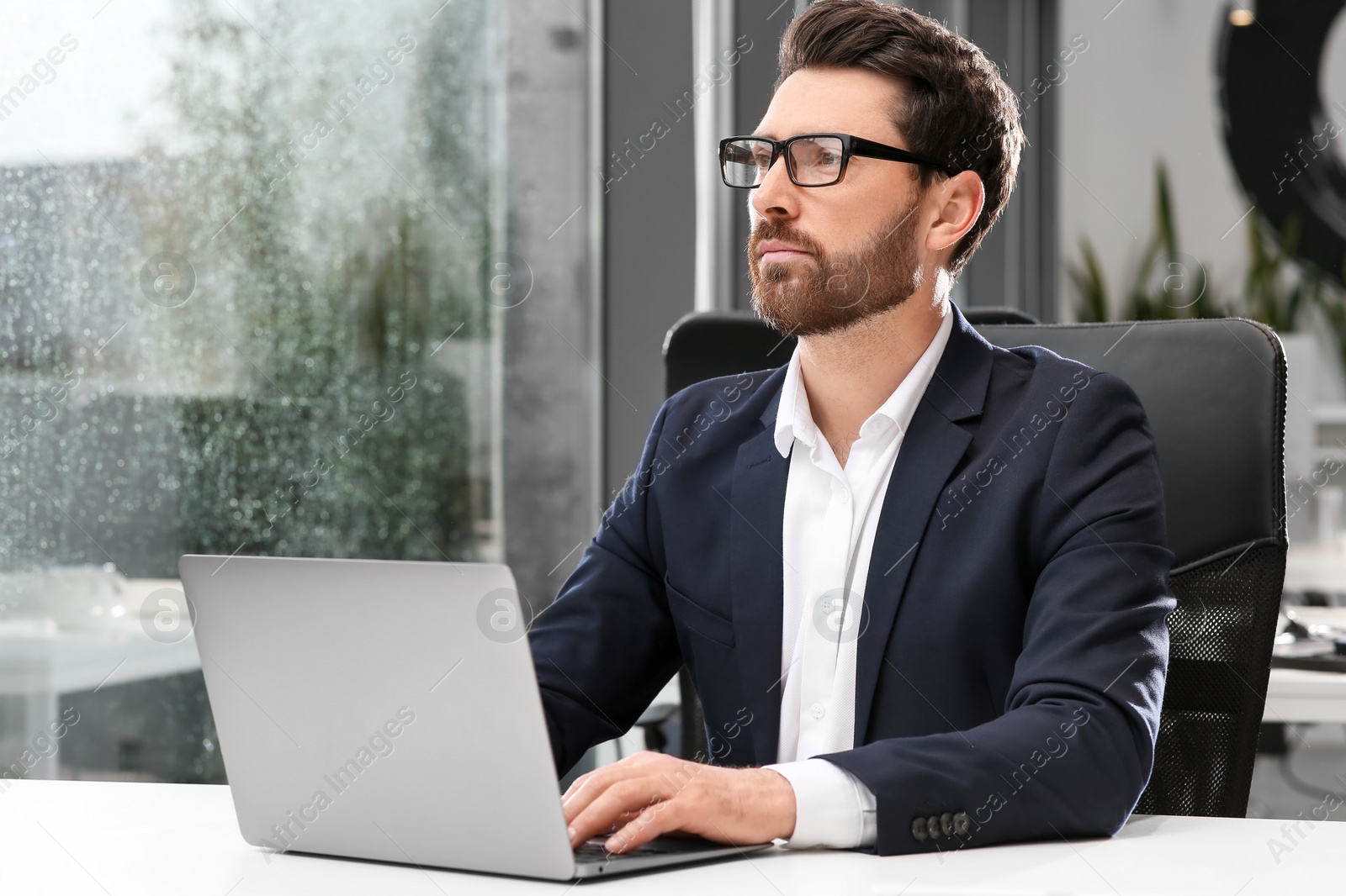 Photo of Man working on laptop at white desk in office