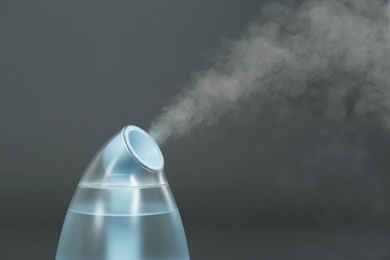 Photo of Modern air humidifier on grey background, closeup. Space for text