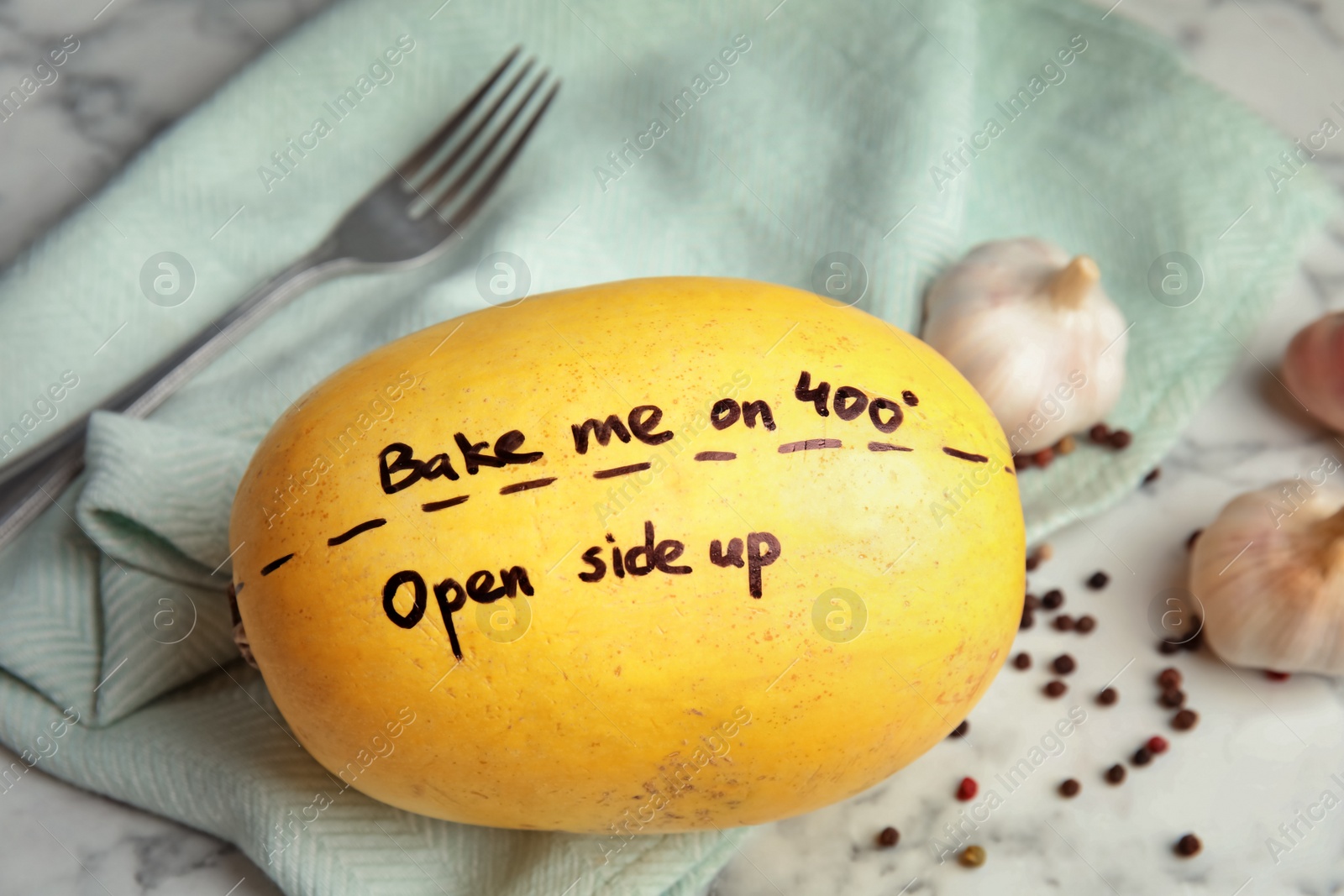 Photo of Ripe spaghetti squash with cooking instructions on marble table