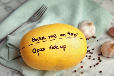 Photo of Ripe spaghetti squash with cooking instructions on marble table