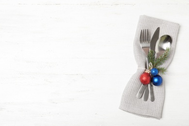 Cutlery, napkin and Christmas decor on wooden background, top view with space for text. Festive table setting