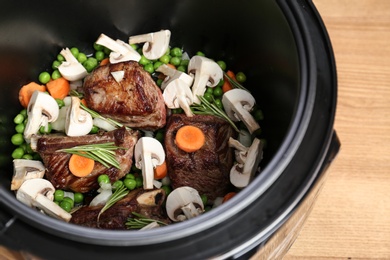 Delicious pork ribs with vegetables in multi cooker on table, closeup