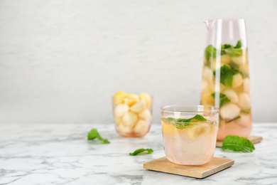 Photo of Glass with tasty melon ball drink on table. Space for text