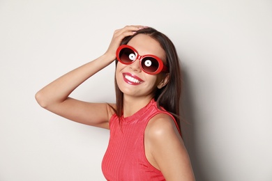 Photo of Beautiful woman in stylish sunglasses on light background