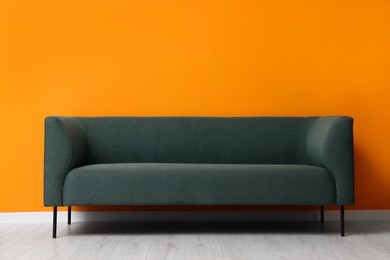 Photo of Stylish sofa near orange wall. Interior design