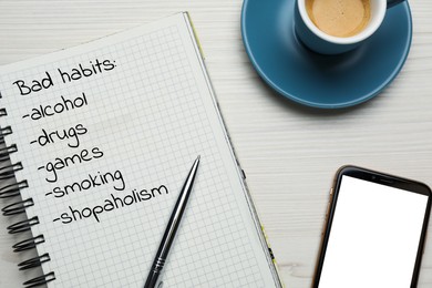 Image of Notebook with list of bad habits, cup of coffee and smartphone on white wooden table, flat lay