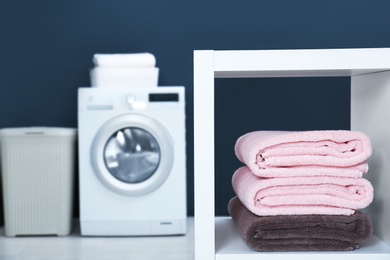 Photo of Stack of clean towels on shelf in laundry room. Space for text