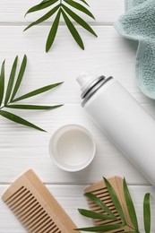 Photo of Dry shampoo spray, combs, towel and green twigs on white wooden table, flat lay