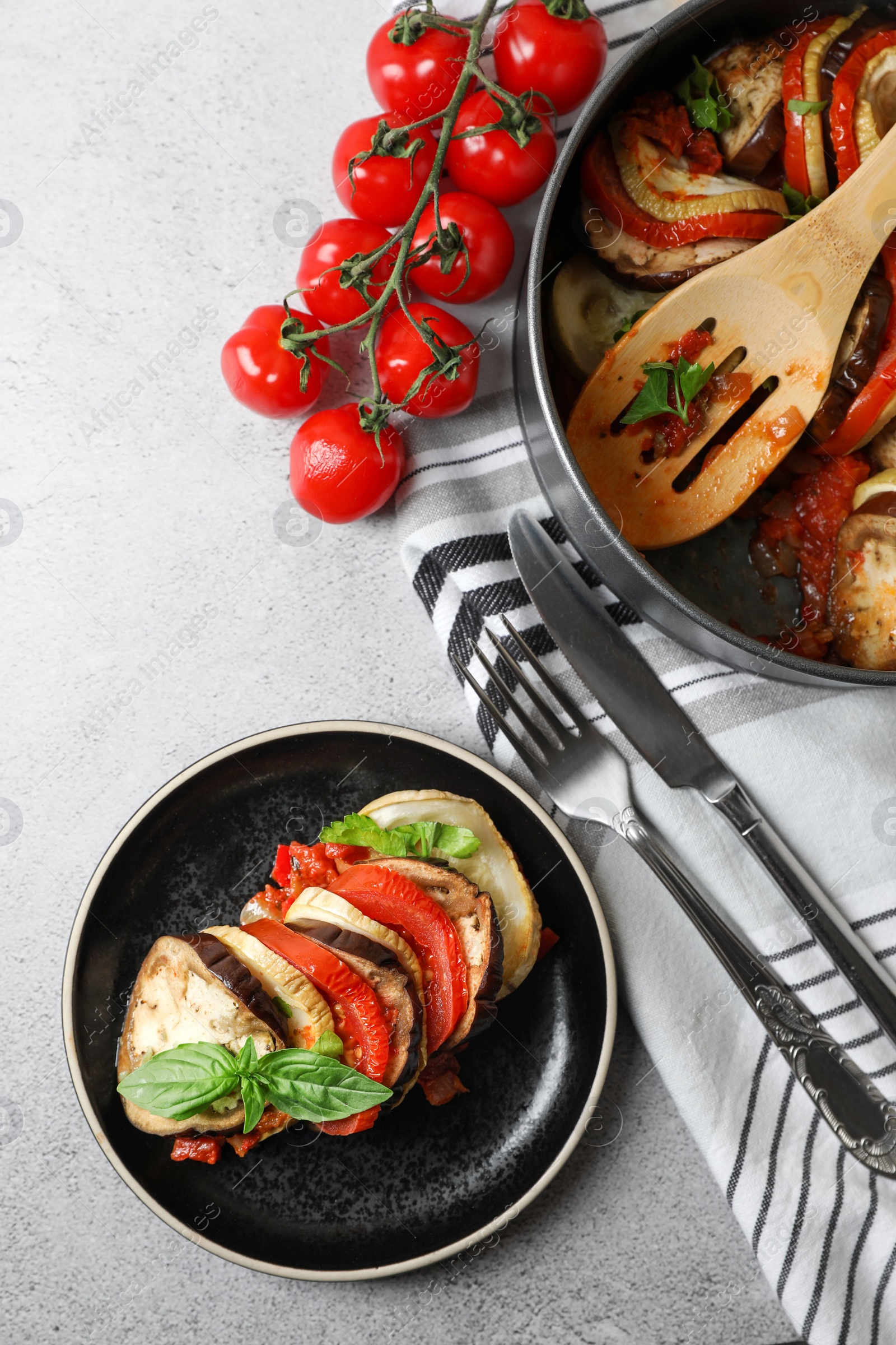 Photo of Delicious ratatouille served with basil on light grey table, flat lay