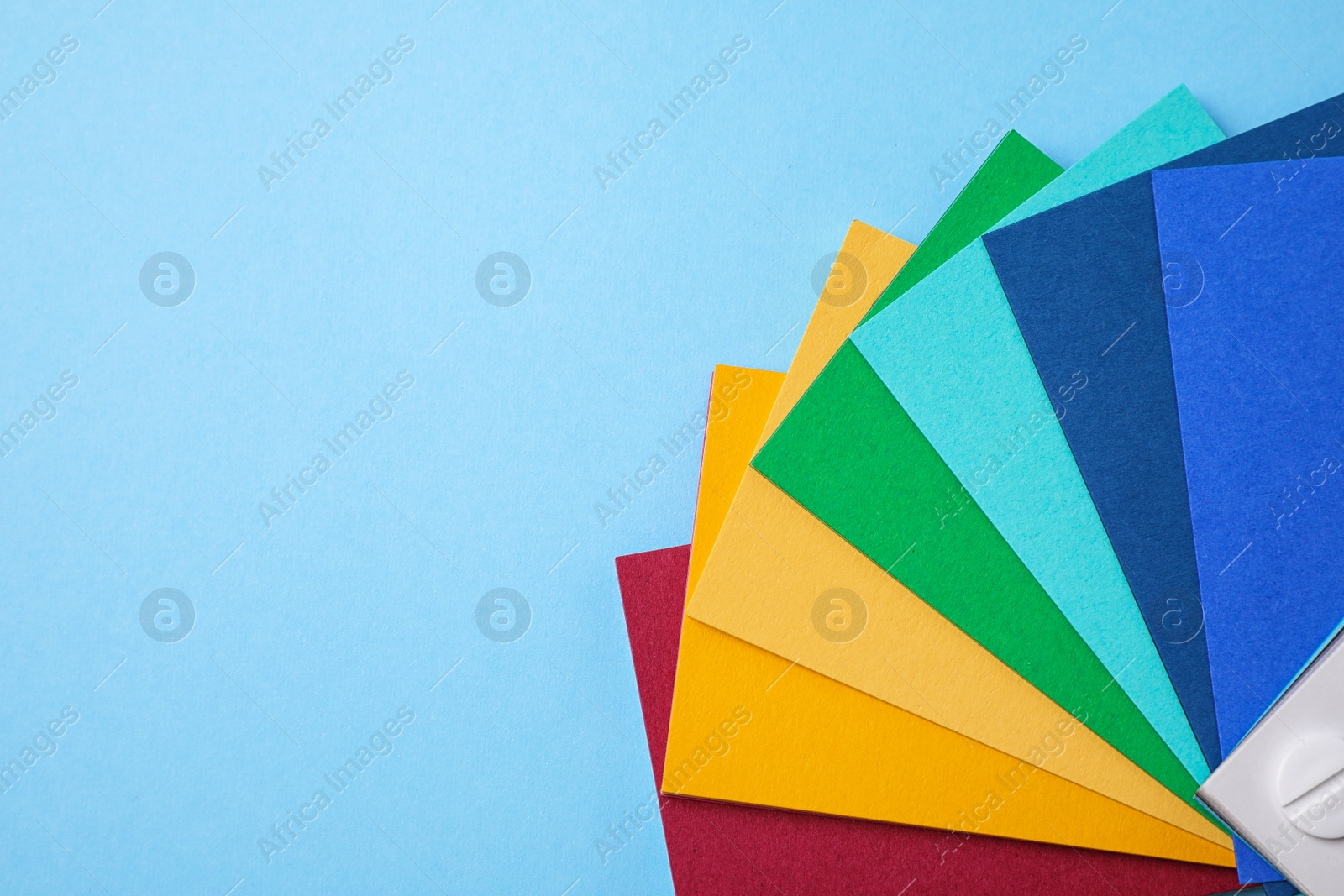 Photo of Multicolored paper sheets and space for text on light blue background, flat lay. Rainbow palette