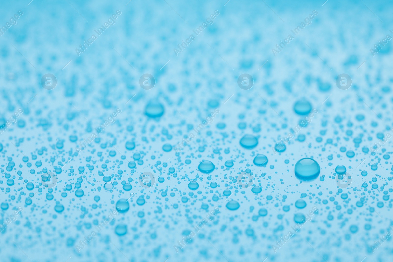 Photo of Water drops on light blue background, closeup view