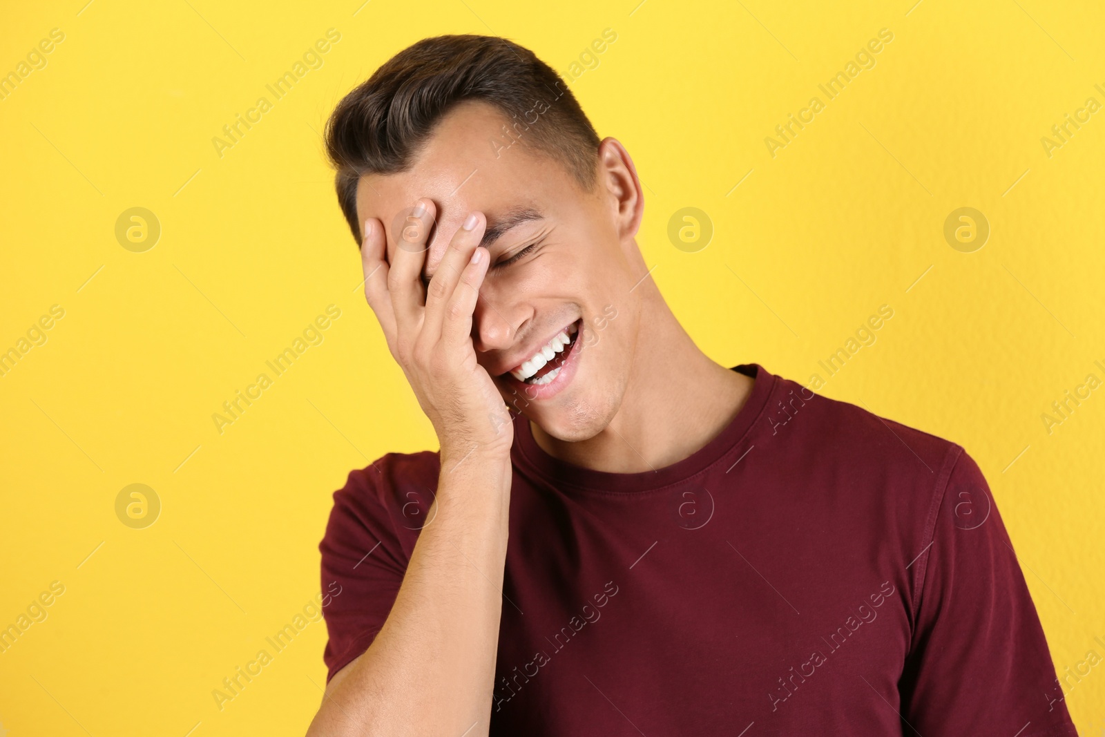 Photo of Portrait of handsome young man laughing on color background