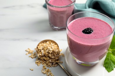 Photo of Glasses of blackberry smoothie with mint and oatmeal on white table, closeup. Space for text