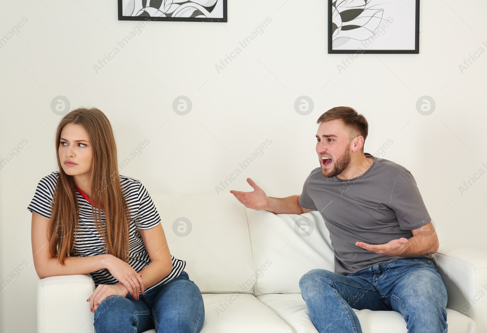 Photo of Young couple having argument in living room. Relationship problems