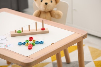 Photo of Stacking and counting game on table indoors. Educational toy for motor skills development