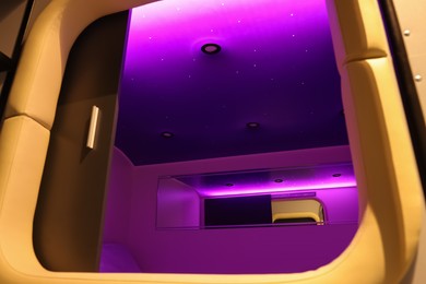 Capsule with purple light in modern pod hostel, low angle view