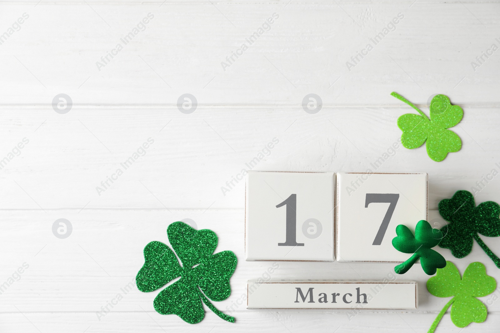 Photo of Flat lay composition with block calendar on white wooden background, space for text. St. Patrick's Day celebration