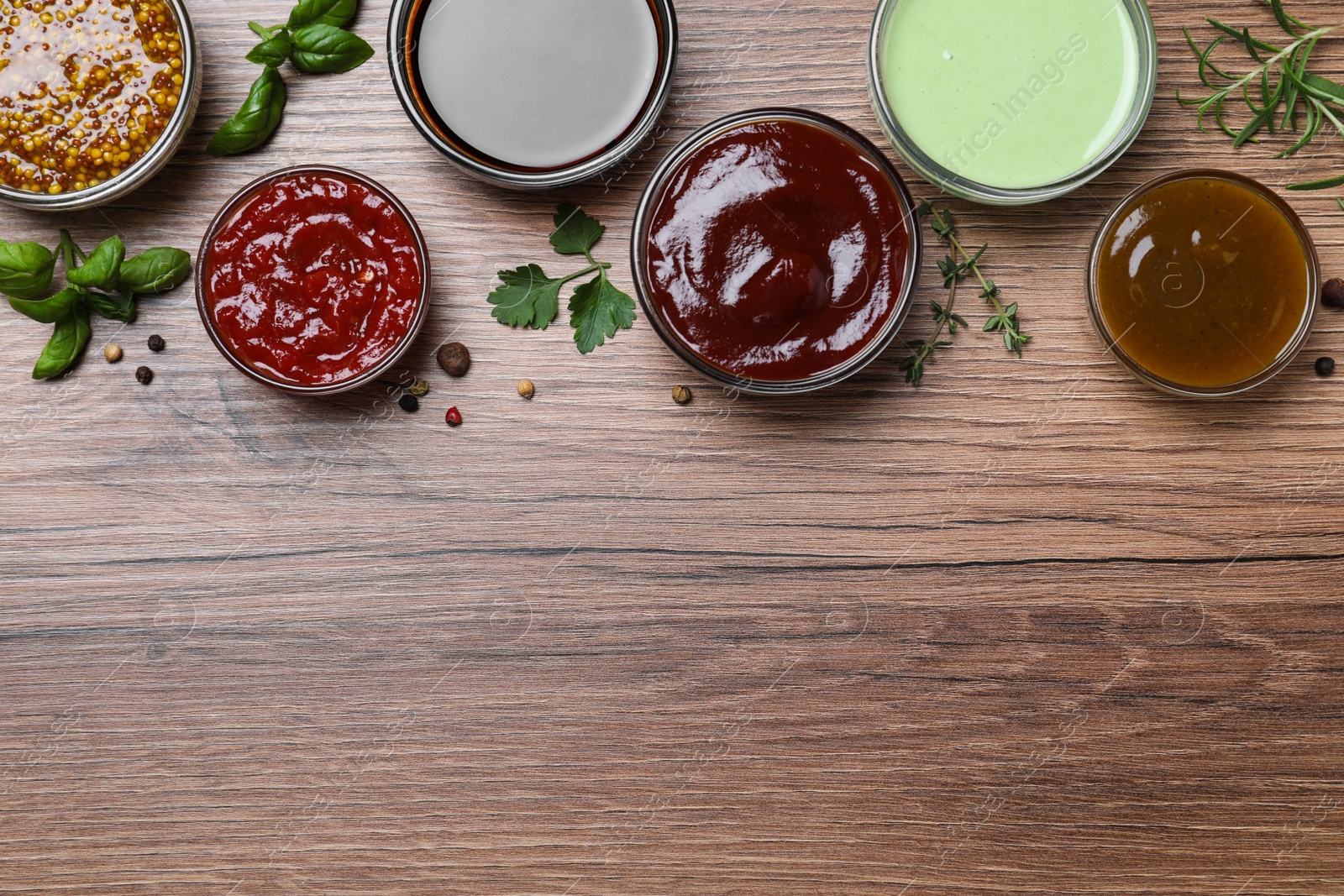 Photo of Many different sauces on wooden table, flat lay. Space for text