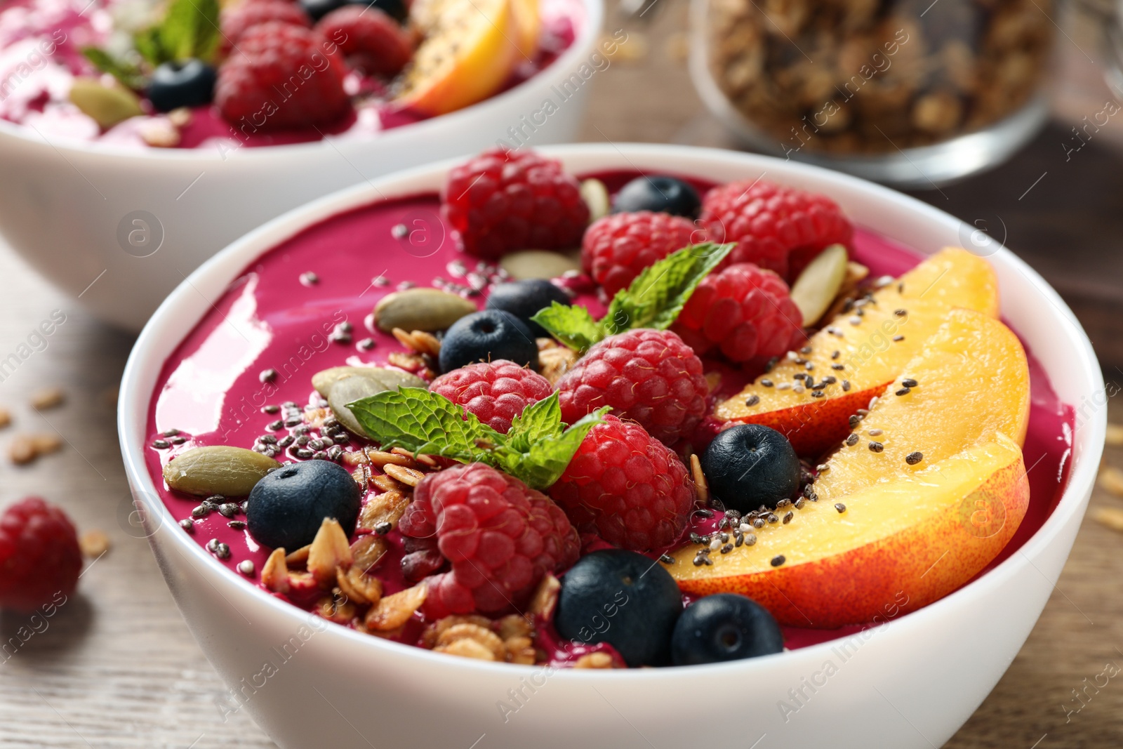 Photo of Delicious acai smoothie with granola and berries in bowl on wooden table, closeup