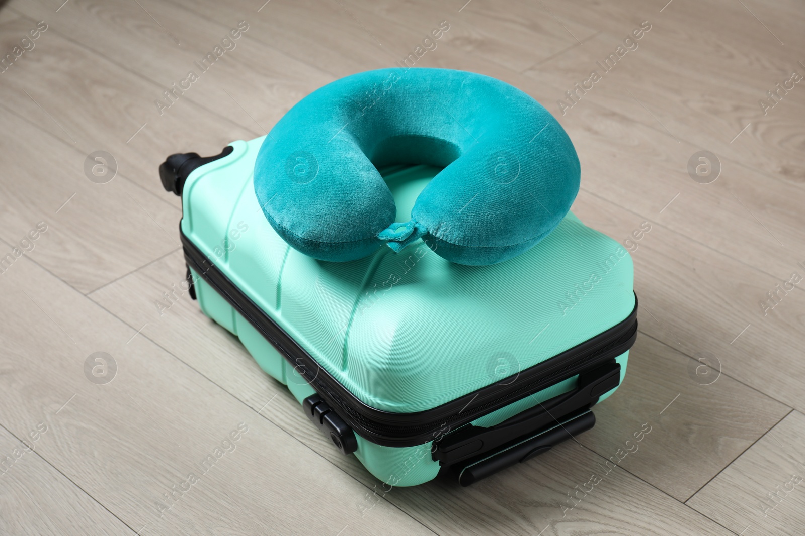 Photo of Turquoise travel pillow and suitcase on floor