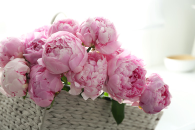 Photo of Basket with beautiful pink peonies in kitchen, closeup