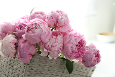 Basket with beautiful pink peonies in kitchen, closeup