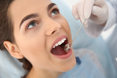 Photo of Dentist examining patient's teeth in modern clinic