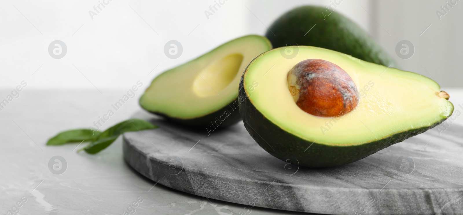 Image of Halves of ripe avocado on table, space for text. Banner design