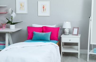 Modern teenager's room interior with comfortable bed and workplace