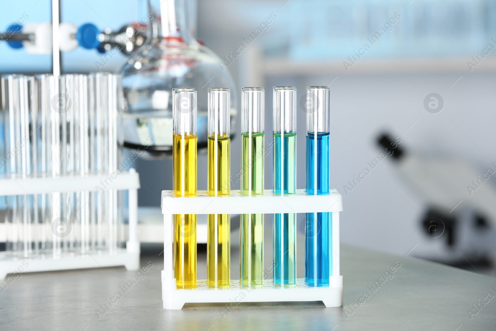 Photo of Test tubes with colorful liquids on grey stone table in laboratory