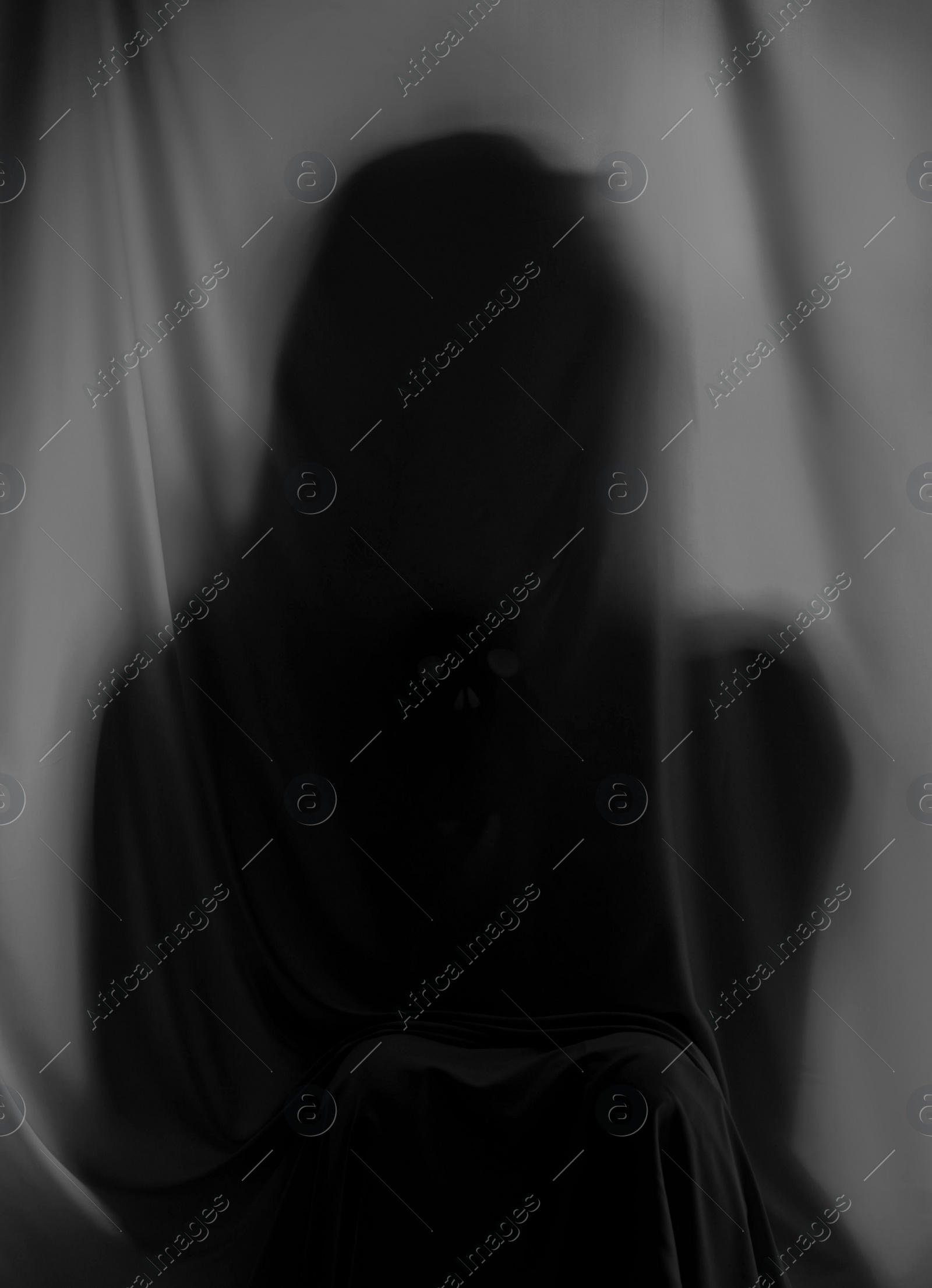 Photo of Silhouette of creepy ghost behind grey cloth