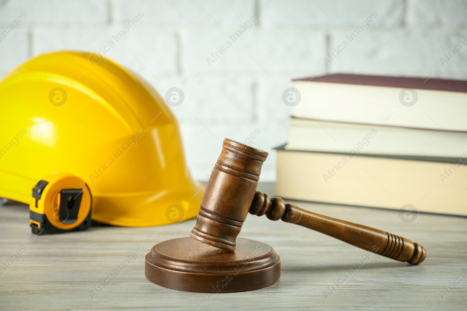 Photo of Construction and land law concepts. Judge gavel, protective helmet, tape measure with books on wooden table