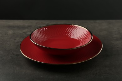 Photo of Red ceramic plate and bowl on gray table, closeup