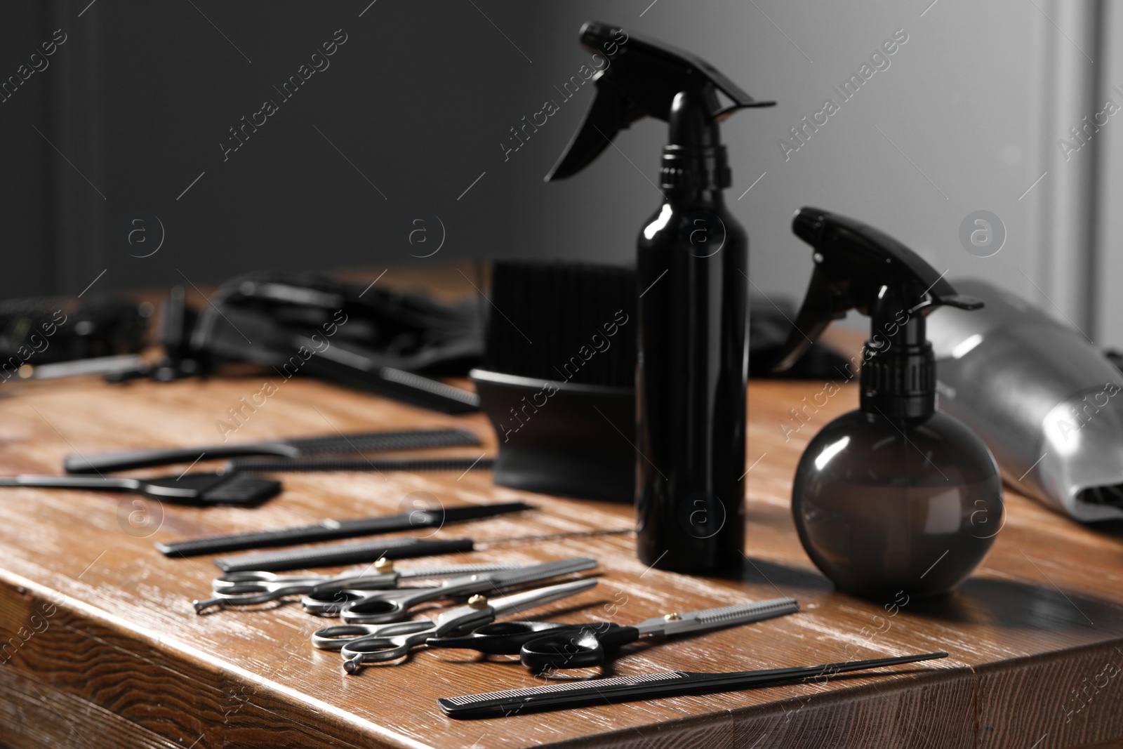 Photo of Hairdresser tools. Different scissors and combs on wooden table in salon, closeup