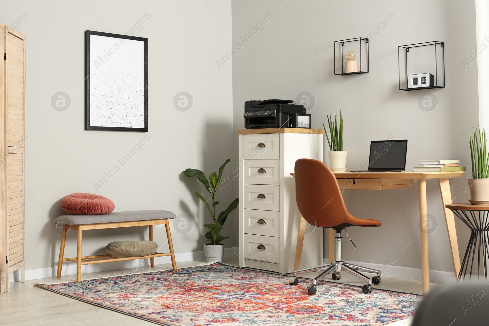 Photo of Stylish room interior with chest of drawers, modern printer and laptop