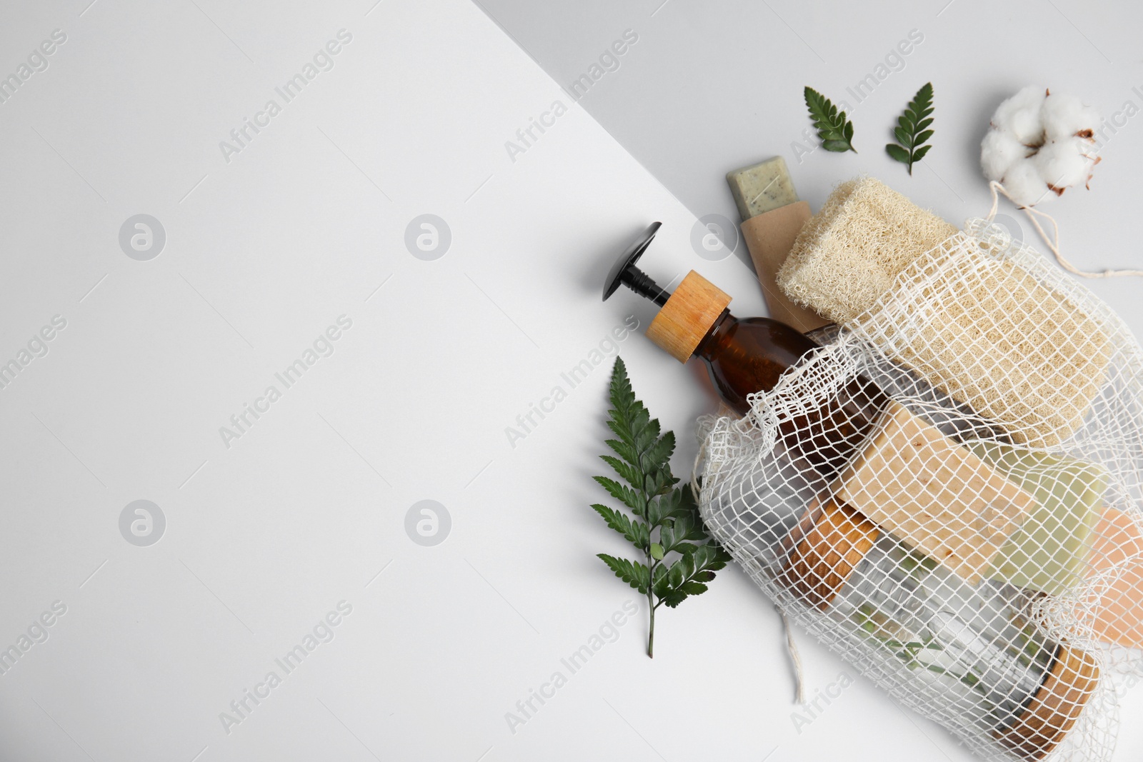 Photo of Mesh bag with eco friendly personal care products on color background, flat lay. Space for text