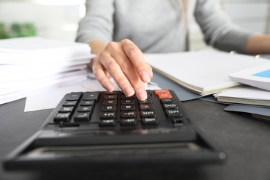 Photo of Office employee working with calculator and documents at table, closeup