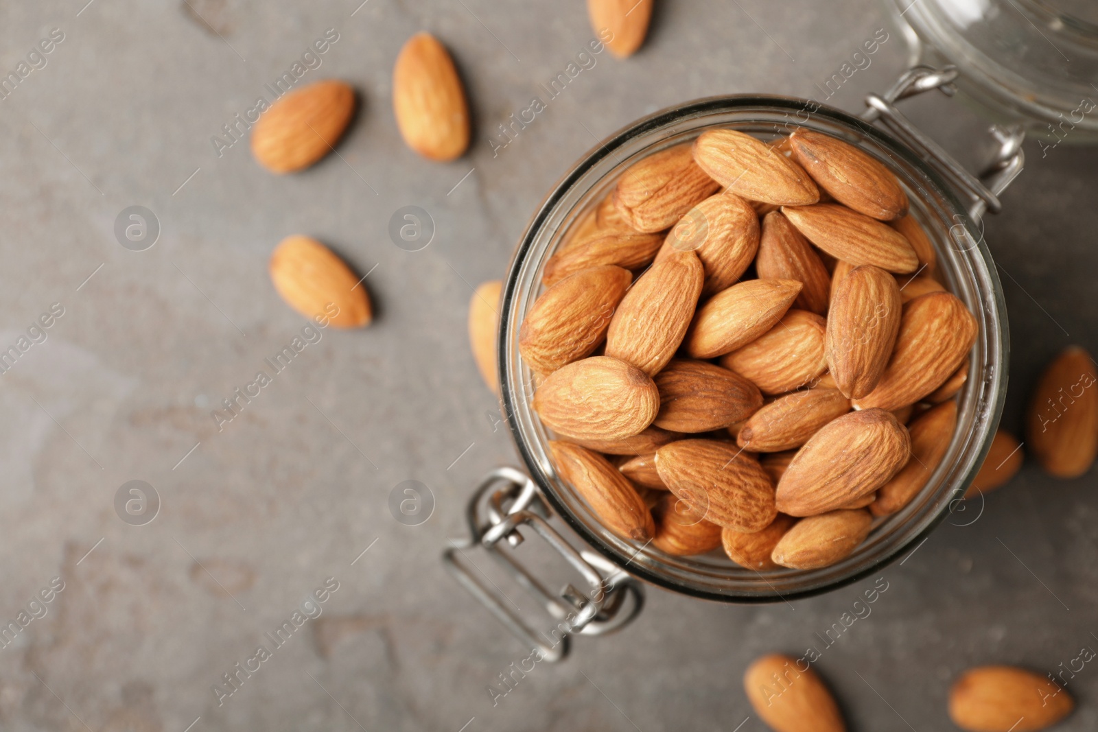 Photo of Tasty organic almond nuts in jar and space for text on table, top view
