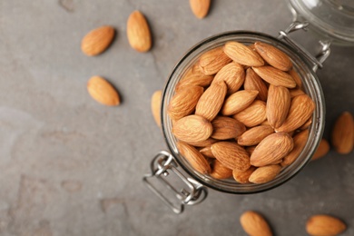Tasty organic almond nuts in jar and space for text on table, top view