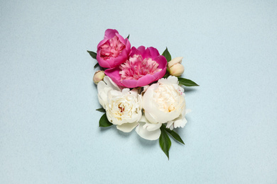 Photo of Beautiful fresh peonies and leaves on light blue background, flat lay
