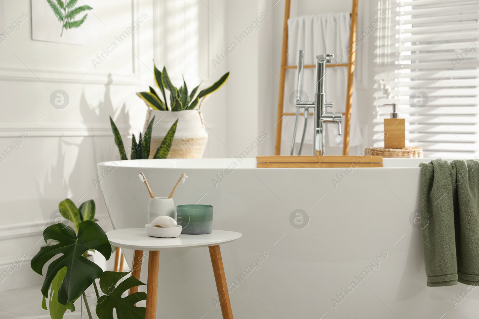 Photo of Toothbrushes and soap on table near bathtub indoors. Interior design