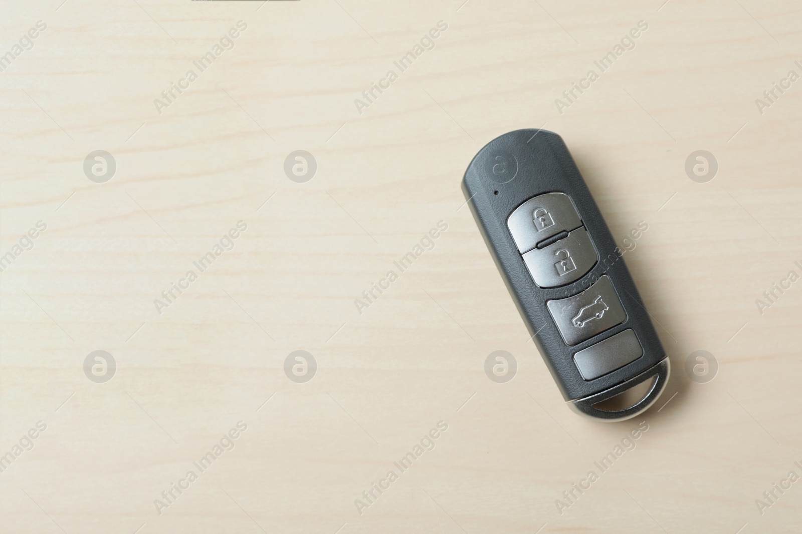 Photo of Remote car key on wooden background, top view. Space for text