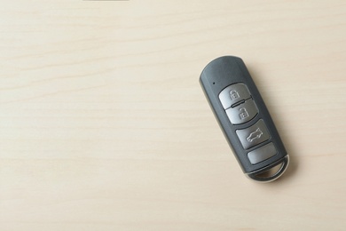 Photo of Remote car key on wooden background, top view. Space for text