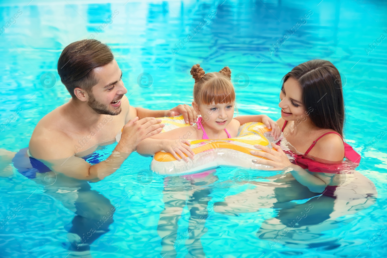 Photo of Happy family with inflatable ring in swimming pool