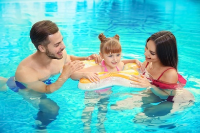 Happy family with inflatable ring in swimming pool