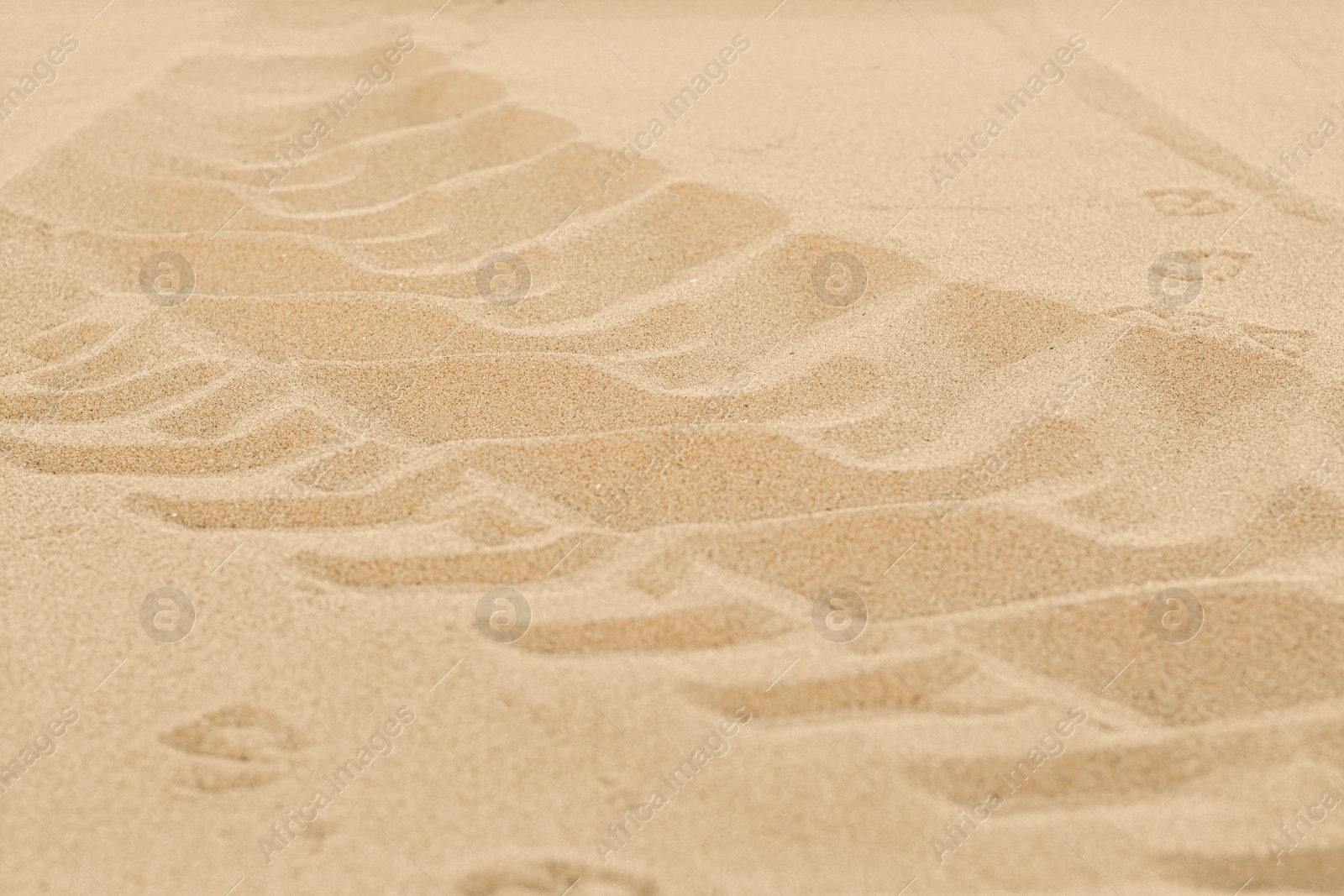 Photo of Car tire tracks on beach sand, closeup