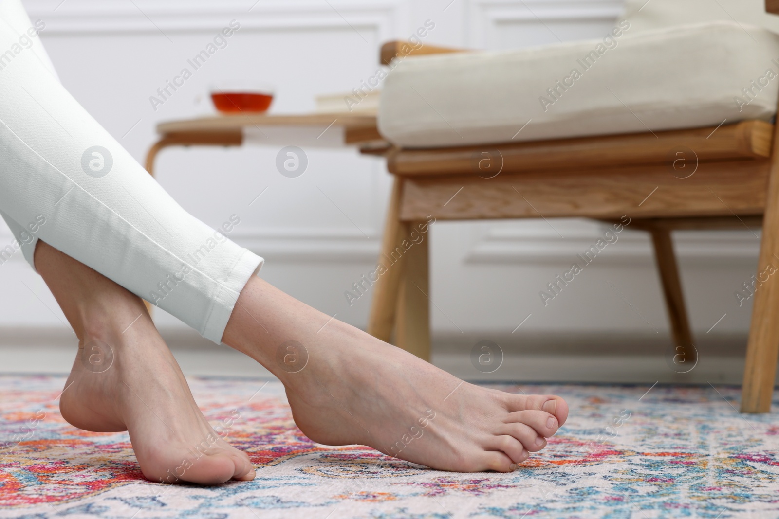 Photo of Woman on carpet with pattern at home, closeup. Space for text