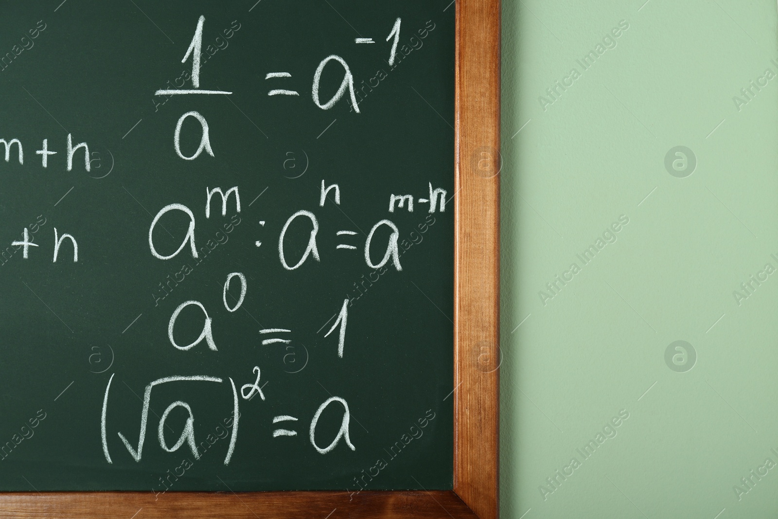 Photo of Chalkboard with many different math formulas on green wall, closeup